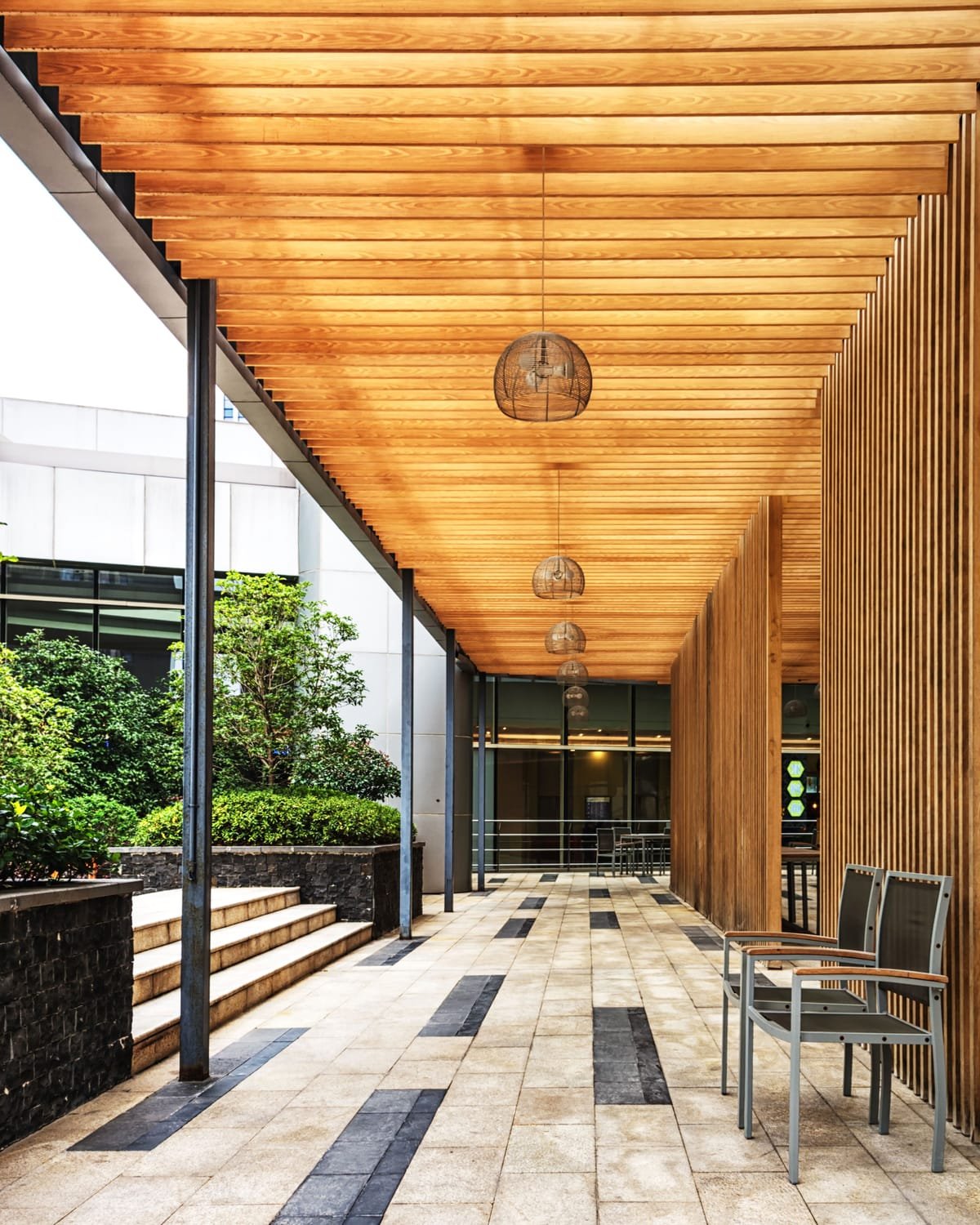 Porche con techo de listones de madera, columnas y revestimientos verticales en madera natural